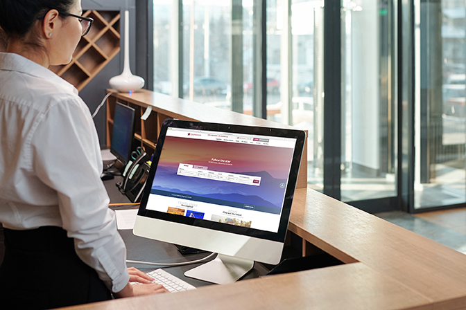 Young,Elegant,Female,Receptionist,Standing,In,Front,Of,Computer,Screen